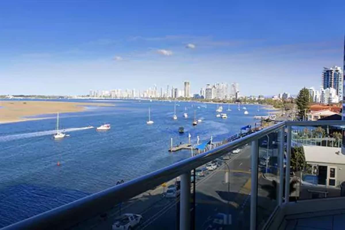 A coastal cityscape with a marina filled with boats, a beach, and high-rise buildings in the background.