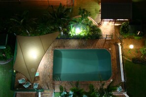 An aerial view of a rooftop pool area with a rectangular pool, surrounded by potted plants and a seating area with chairs. - Beaconlea Tower Apartments (Labrador)