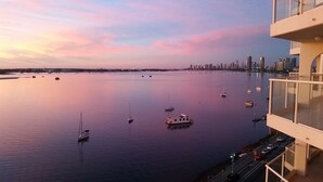 A waterfront view with boats, a city skyline, and a modern building with balconies. - Beaconlea Tower Apartments (Labrador)