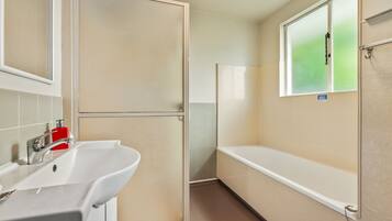 Een badkamer met een wastafel, spiegel en douchecabine.