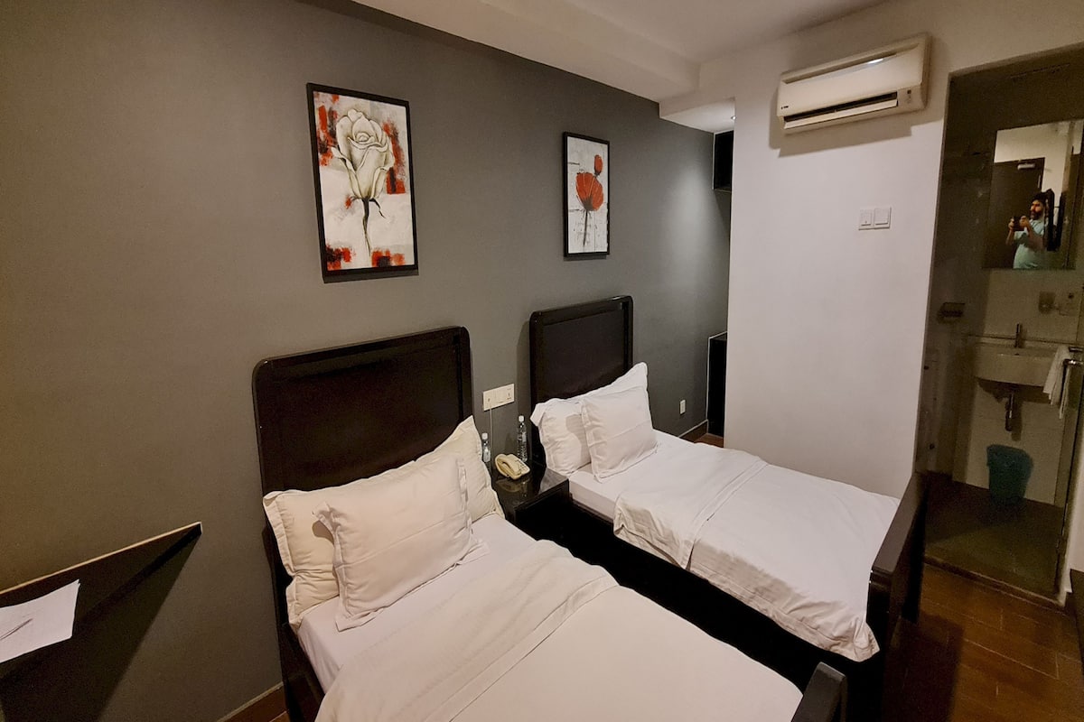 Habitación de hotel con dos camas, una mesita de noche, un espejo y obras de arte en la pared.