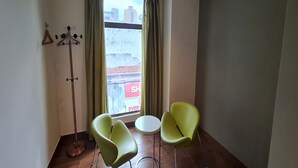 A room with a large window, two green chairs, a small round table, and a floor lamp. - Hotel O Crossroads Hotel (Kuala Lumpur)