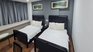 A hotel room with two single beds, a small table, a chair, and a window with curtains. - Hotel O Crossroads Hotel (Kuala Lumpur)
