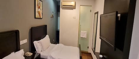 A hotel room with two beds, a TV, an air conditioning unit, and a bathroom door.