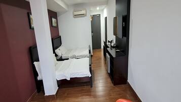 A hotel room with a bed, a desk, a chair, a TV, and a bathroom.