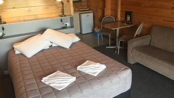 A room with a bed, a small desk, a chair, a sofa, and a microwave.