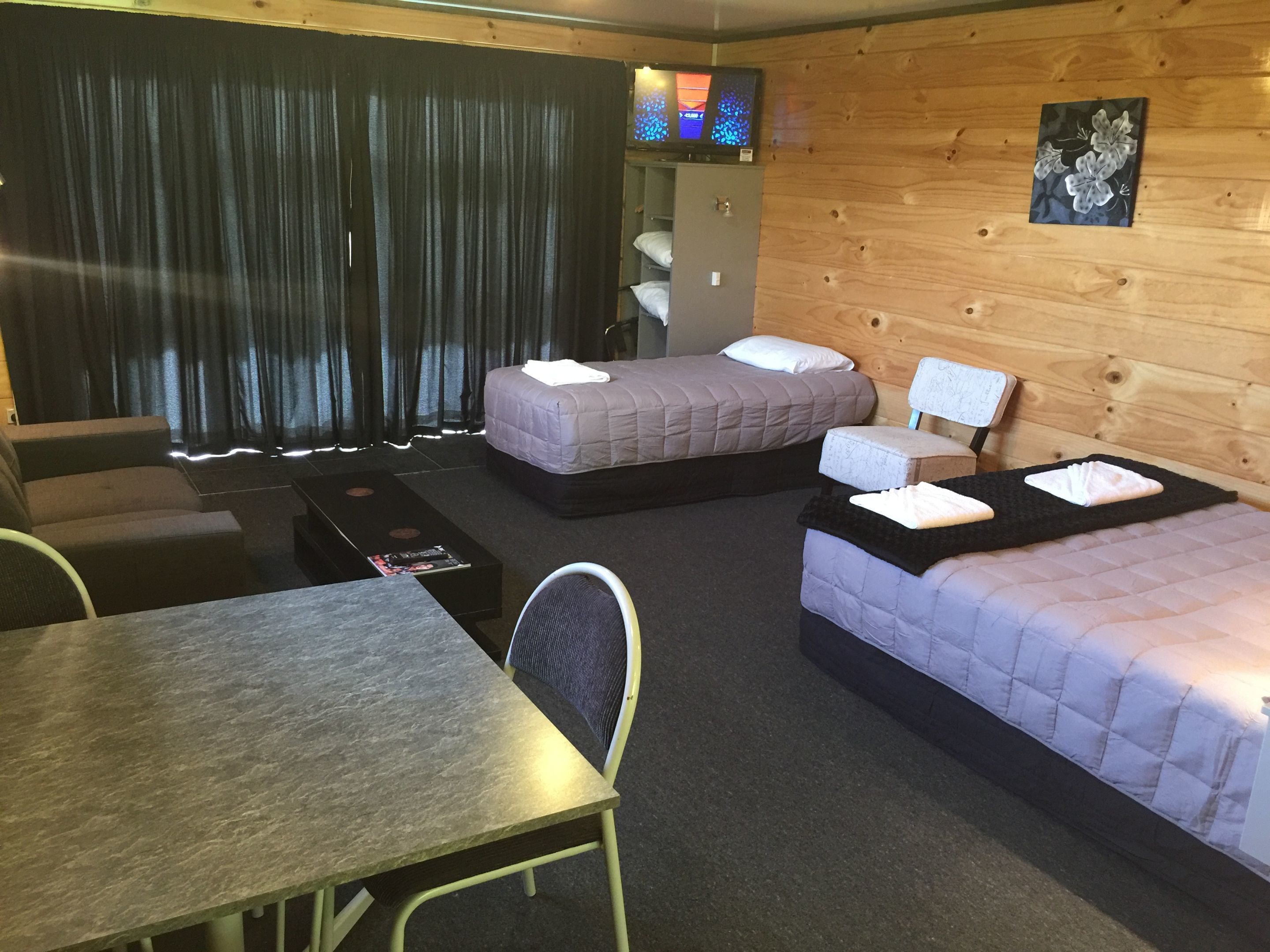 Una habitación con dos camas, una mesa y un televisor en la pared.