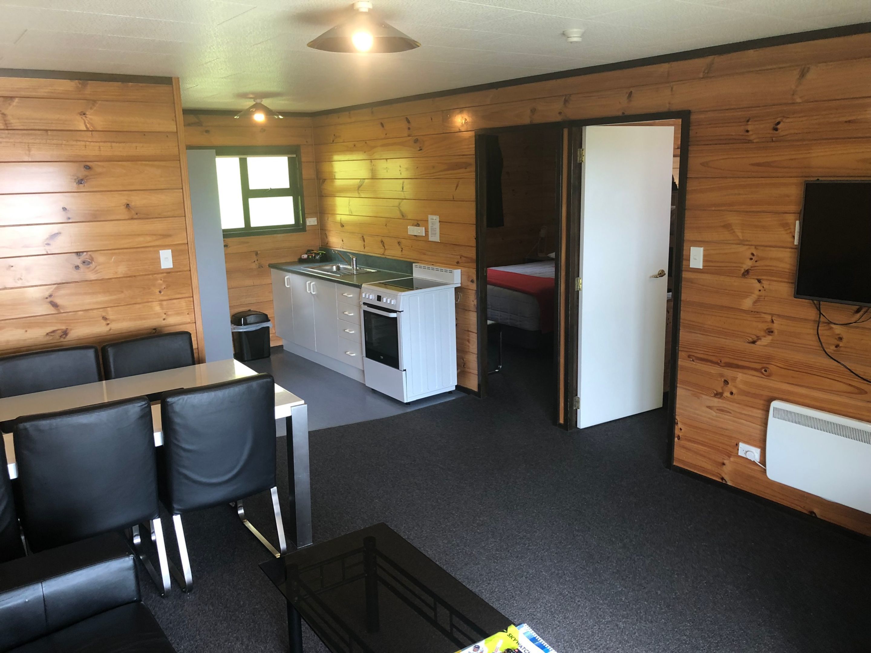 Een compacte kamer met een kitchenette, een eethoek met tafel en stoelen, en een bed in de aangrenzende kamer.