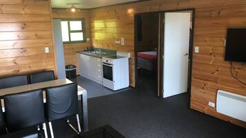 Een compacte kamer met een kitchenette, een eethoek met tafel en stoelen, en een bed in de aangrenzende kamer.