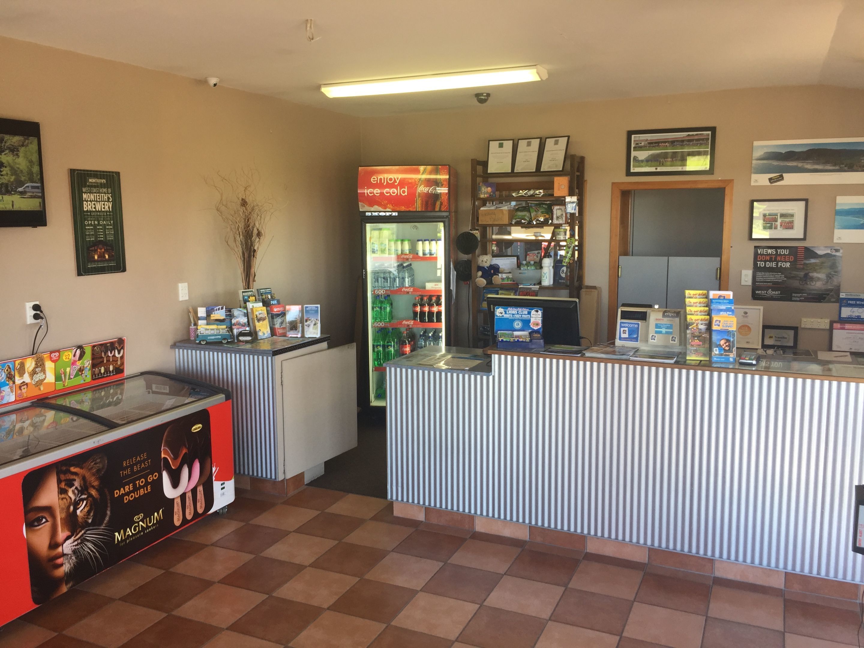A reception area with a counter, a refrigerator stocked with beverages, and various promotional materials on the walls.