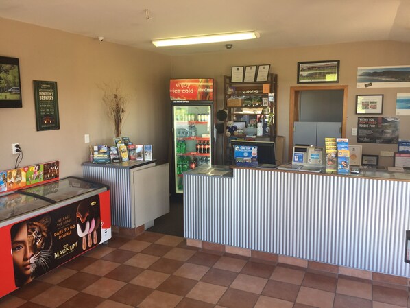 A reception area with a counter, a refrigerator stocked with beverages, and various promotional materials on the walls.