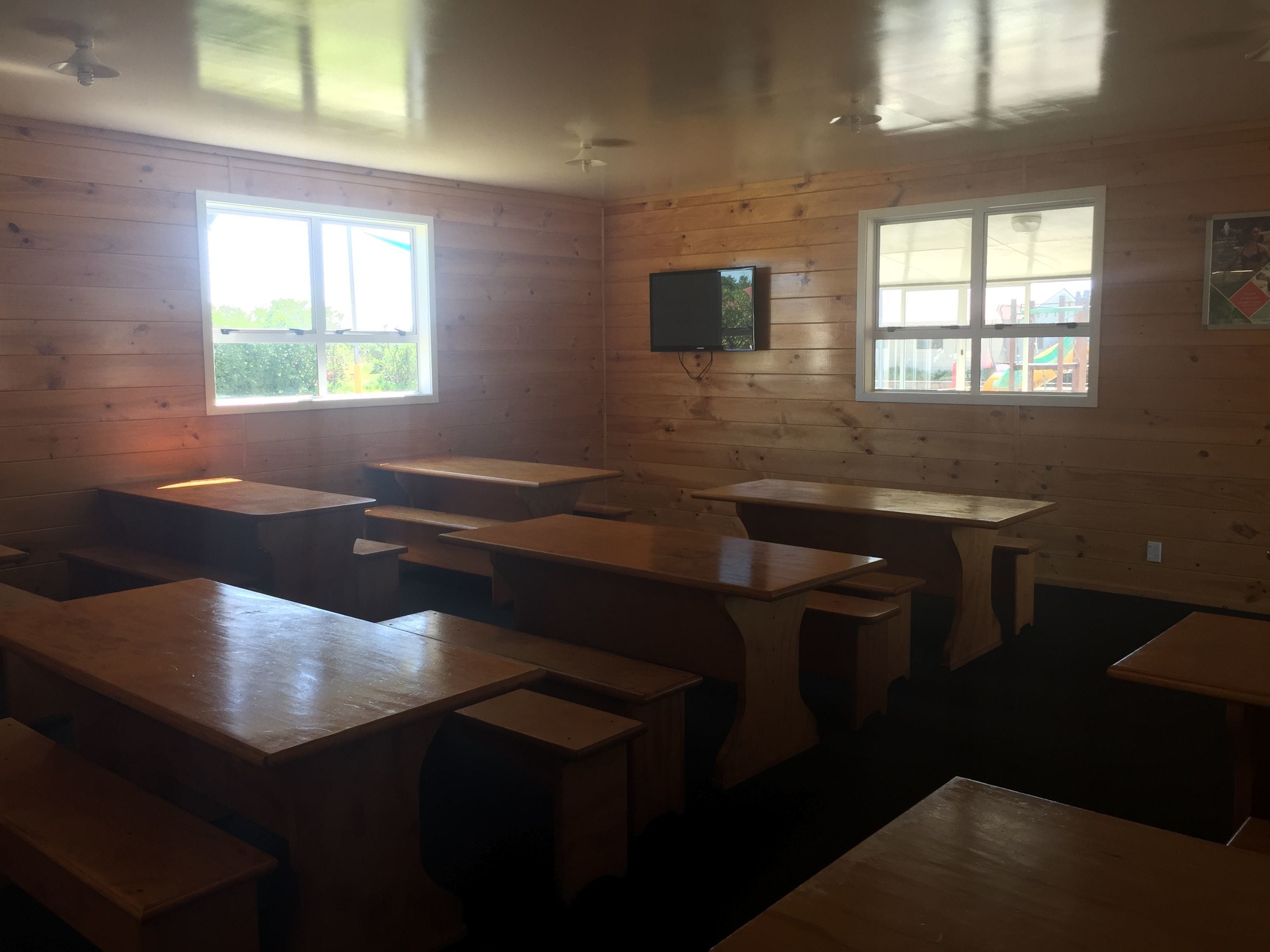 A room with wooden walls and multiple tables and benches.