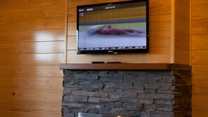 A modern fireplace with a stone facade and a flat-screen TV mounted above it.