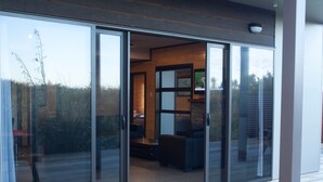 A modern house with a sliding glass door leading to a living area with a sofa and a TV.