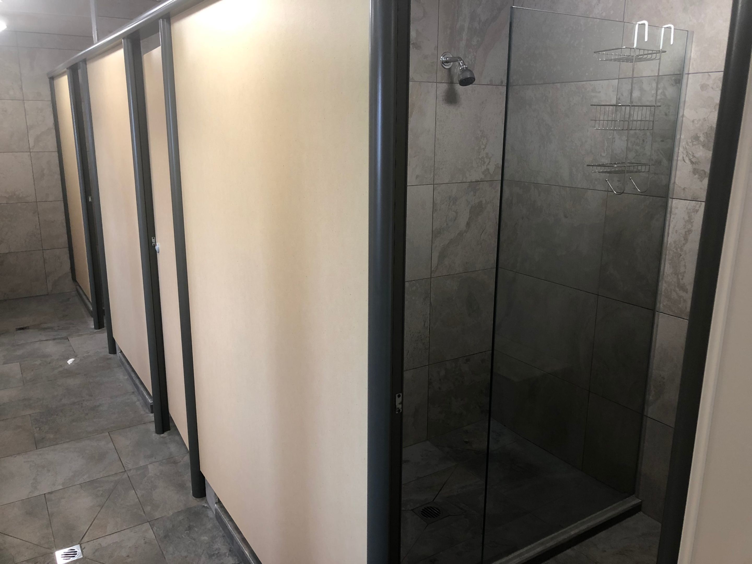 Un bany modern amb una cabina de dutxa de vidre, parets revestides de rajola i un rodet de dutxa amb estructura metàl·lica.