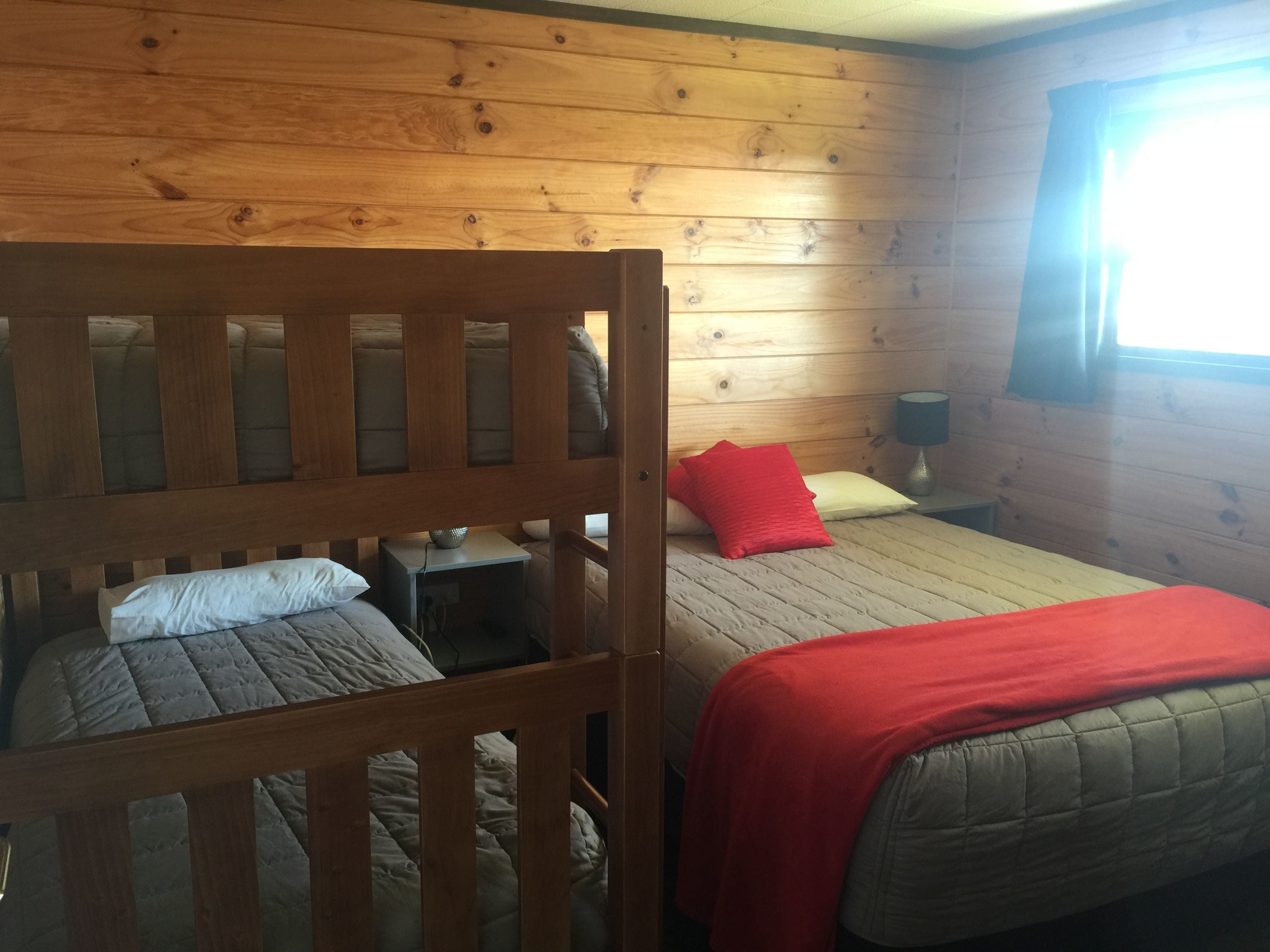 Una habitación de cabaña de madera con dos camas, una mesita y una mesilla de noche.