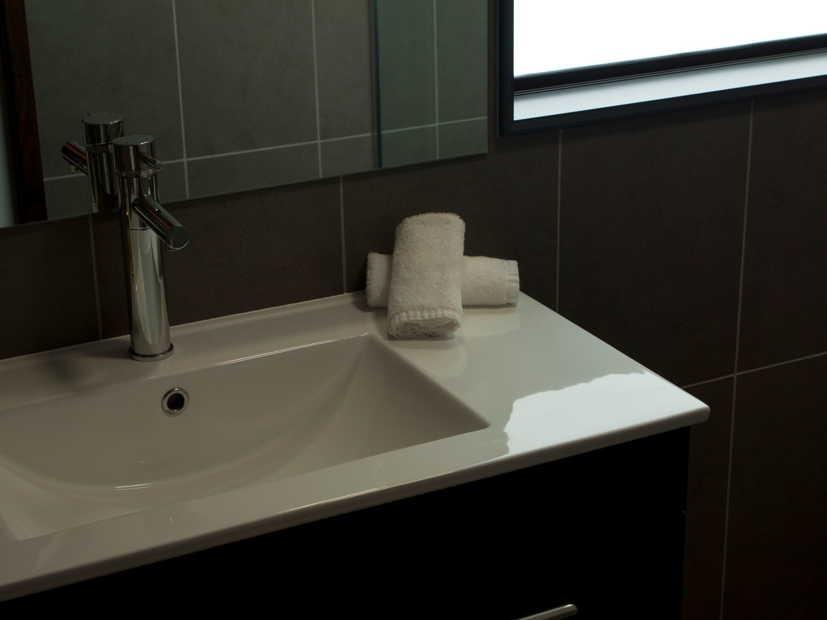 A bathroom with a white sink, a modern faucet, and a mirror.