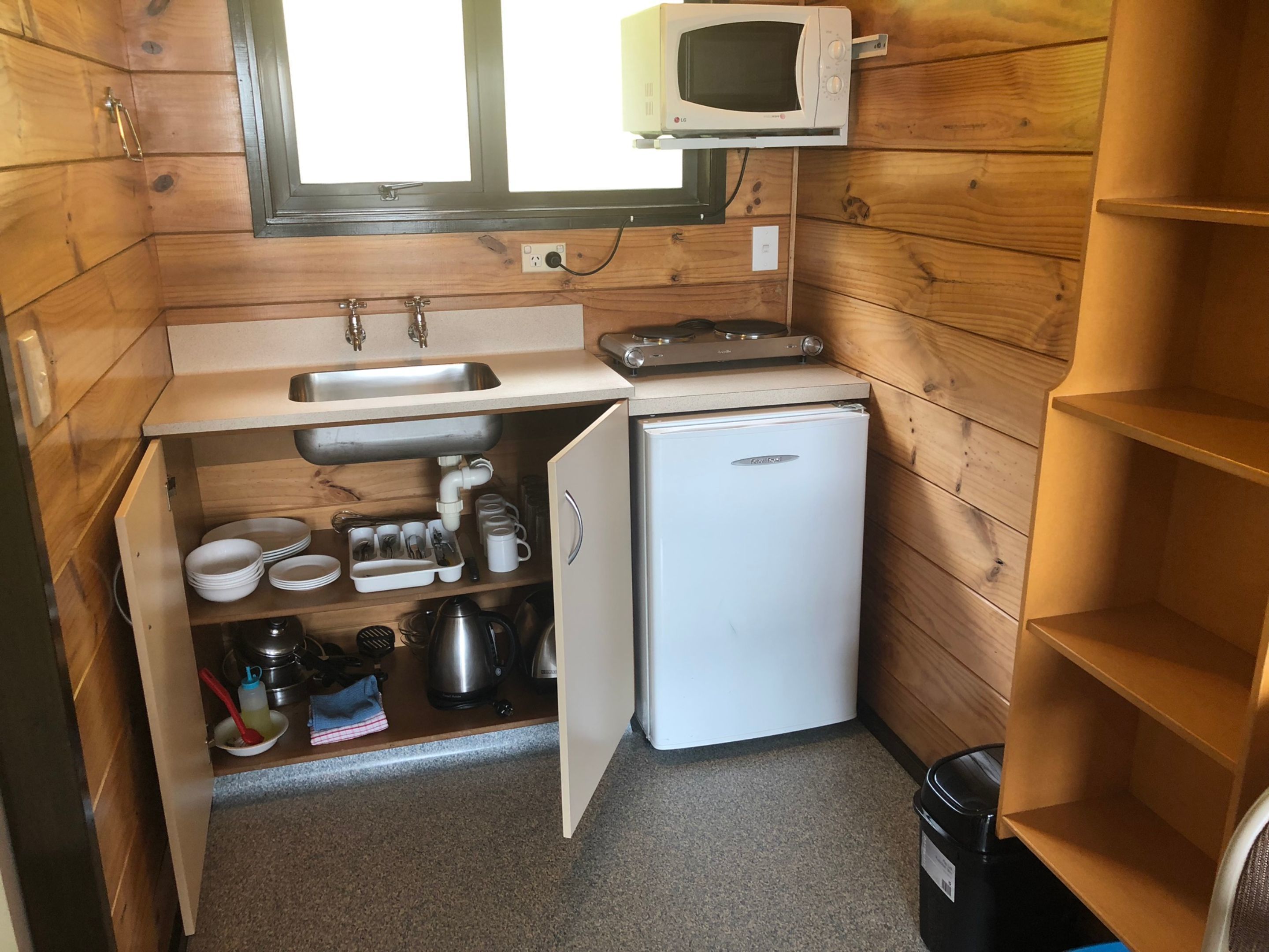 A compact kitchen with a built-in microwave, sink, and refrigerator.