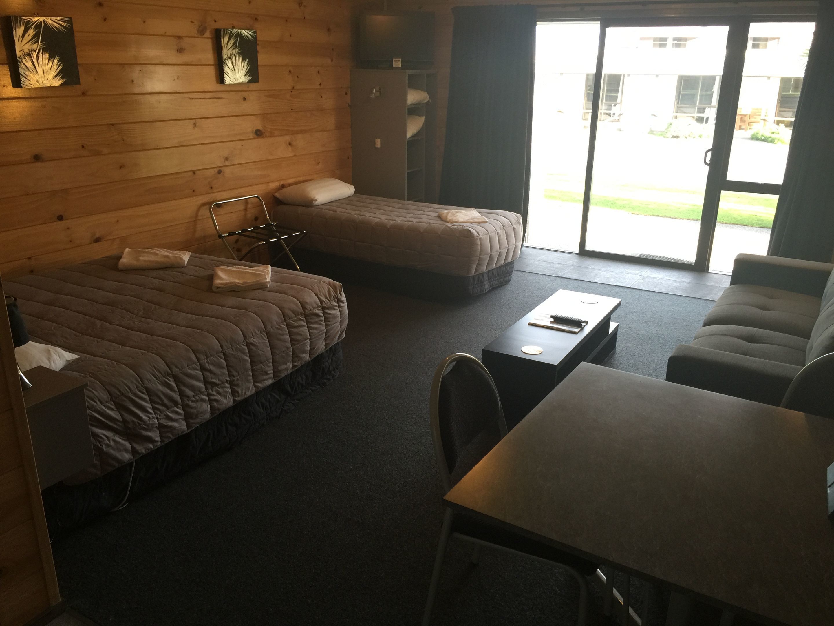 A hotel room with a bed, a sofa, a table, and a chair. There is a window with a view of the outside.