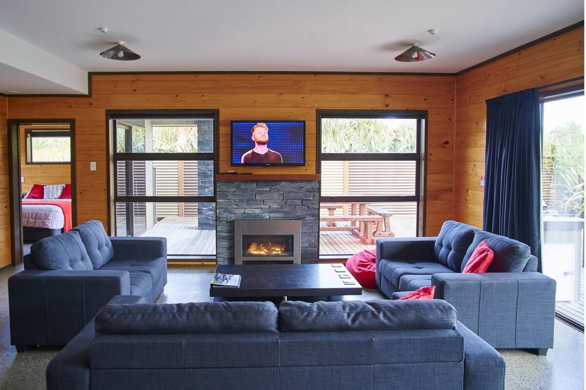 Ein modernes Wohnzimmer mit zwei grauen Sofas, einem Steinkamin und einem an der Wand befestigten Fernseher.