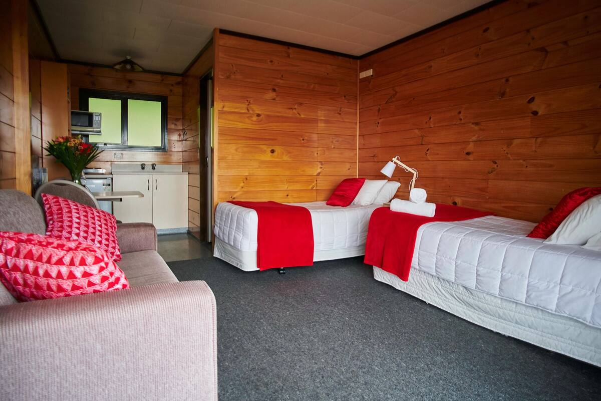 Ein gemütliches Zimmer mit zwei Betten, einer Couch und einer Küchenzeile.