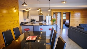 A modern kitchen with a central island, bar stools, and pendant lighting.