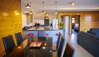Uma cozinha moderna com ilha central, banquetas e iluminação pendente.