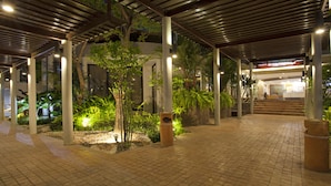 An outdoor covered area with a tiled floor, columns, and potted plants. - Areca Lodge (Pattaya)