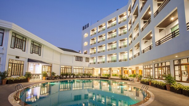 A hotel with a central swimming pool, multiple balconies, and indoor seating areas. - Areca Lodge (Pattaya)