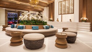 A modern lobby with a central seating area, a reception desk, and a decorative plant arrangement. - Areca Lodge (Pattaya)