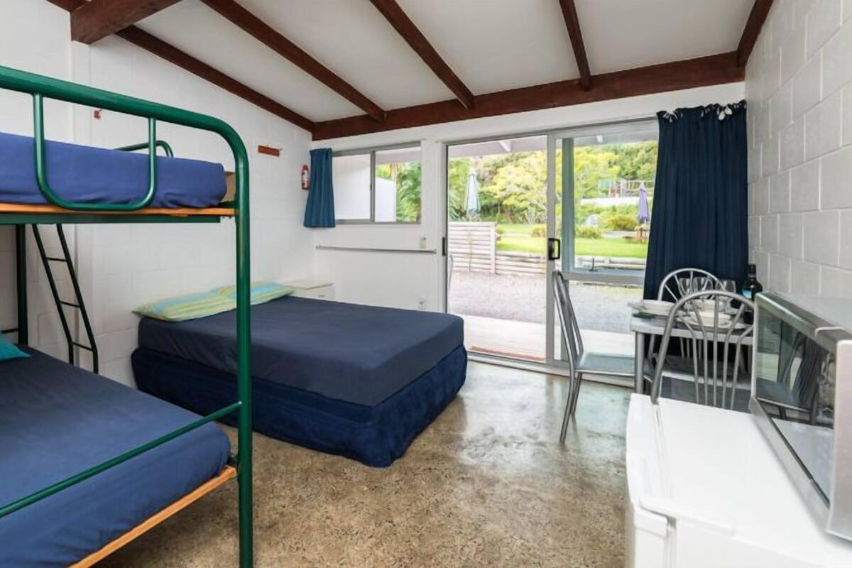 A dormitory room with bunk beds, a small desk, and a chair.