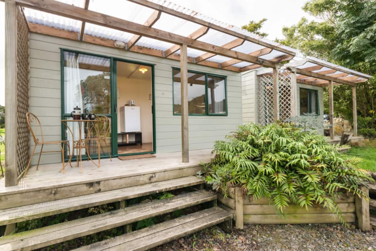 A wooden deck with a bench and a table, a covered patio area, and a garden with various plants.