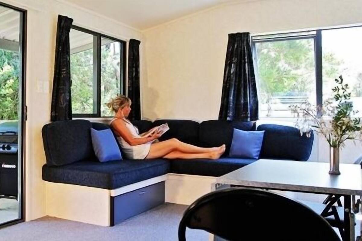 A modern living room with a sectional sofa, a dining table, and a view of greenery outside.