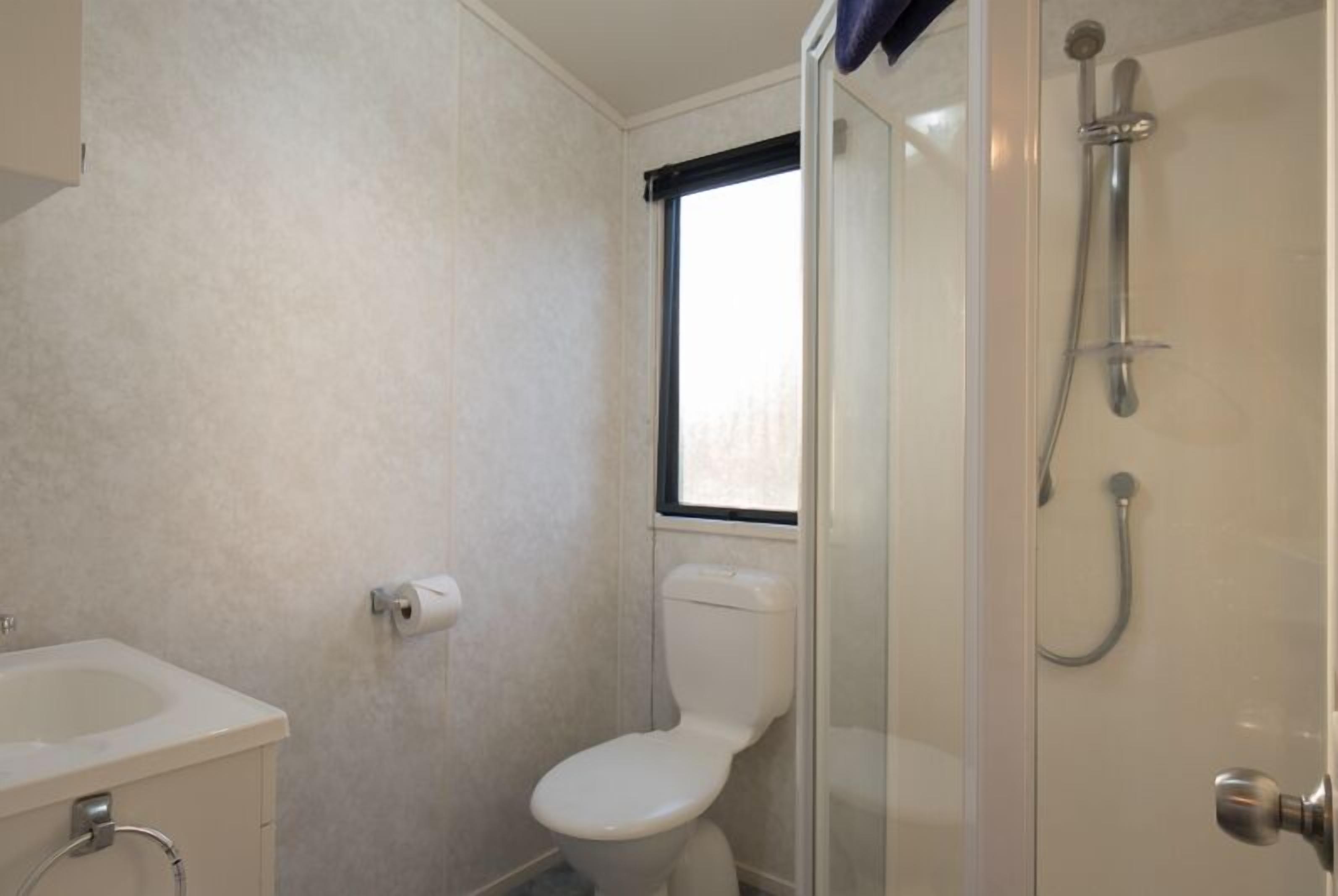 A small, compact bathroom with a toilet, a sink, and a shower.