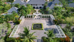 Un complexe hôtelier doté d’une cour centrale, entouré de palmiers et offrant une vue sur la plage.