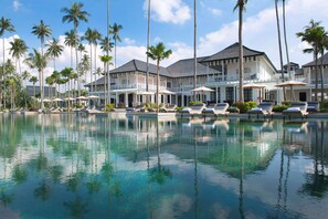 A resort with a pool, lounge chairs, and palm trees. - The Sanchaya (Bintan)