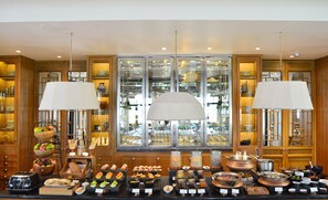 A buffet area with various food items and a display of glassware. - The Sanchaya (Bintan)