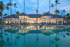 Un gran complejo turístico con piscina, varias habitaciones y palmeras.