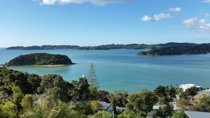 A coastal landscape with a small island, clear skies, and lush greenery. - Tarltons Lodge (Paihia)