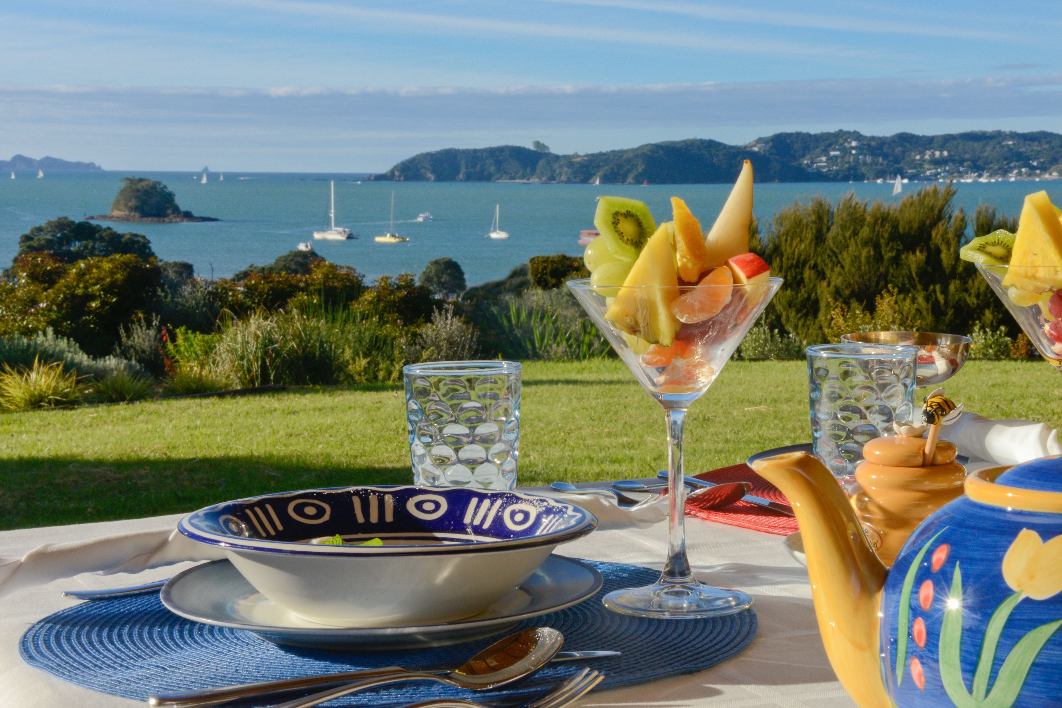 Ein Tisch mit Schale, Martini-Glas und Teekanne, mit Blick auf eine malerische Bucht und Boote.
