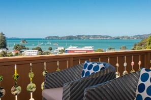 Un balcón con muebles de mimbre y vista al mar.