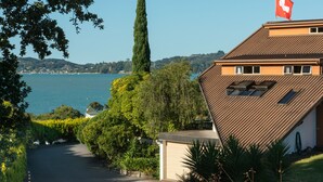 A house with a sloped roof, a flag, and a view of a lake. - Chalet Romantica (Paihia)