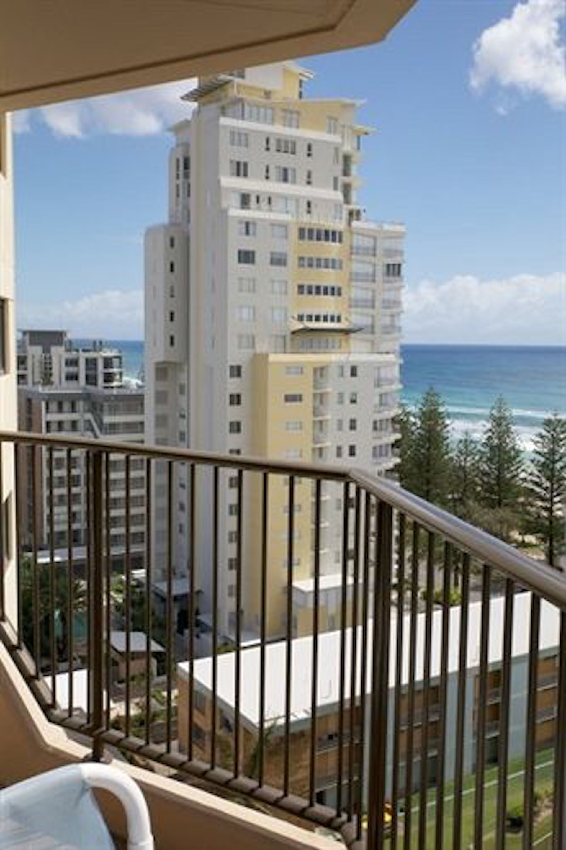 A balcony with a view of a tall building and the ocean.