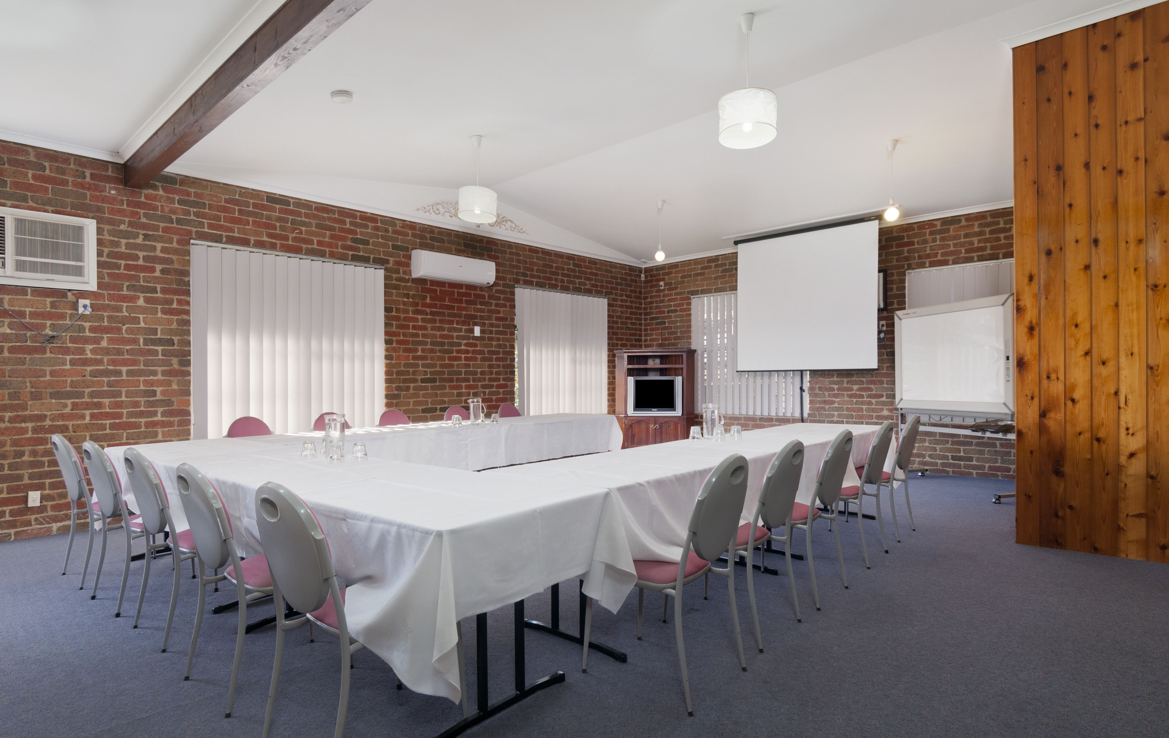 A conference room with a long table, chairs, a projector screen, and a whiteboard.