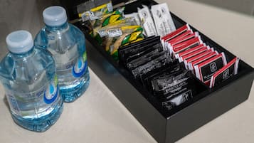 Una caja negra con diversos artículos, como agua embotellada, bocadillos y sobres de café.