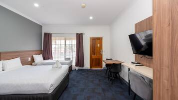 A hotel room with two beds, a desk, a chair, a television, and a door.