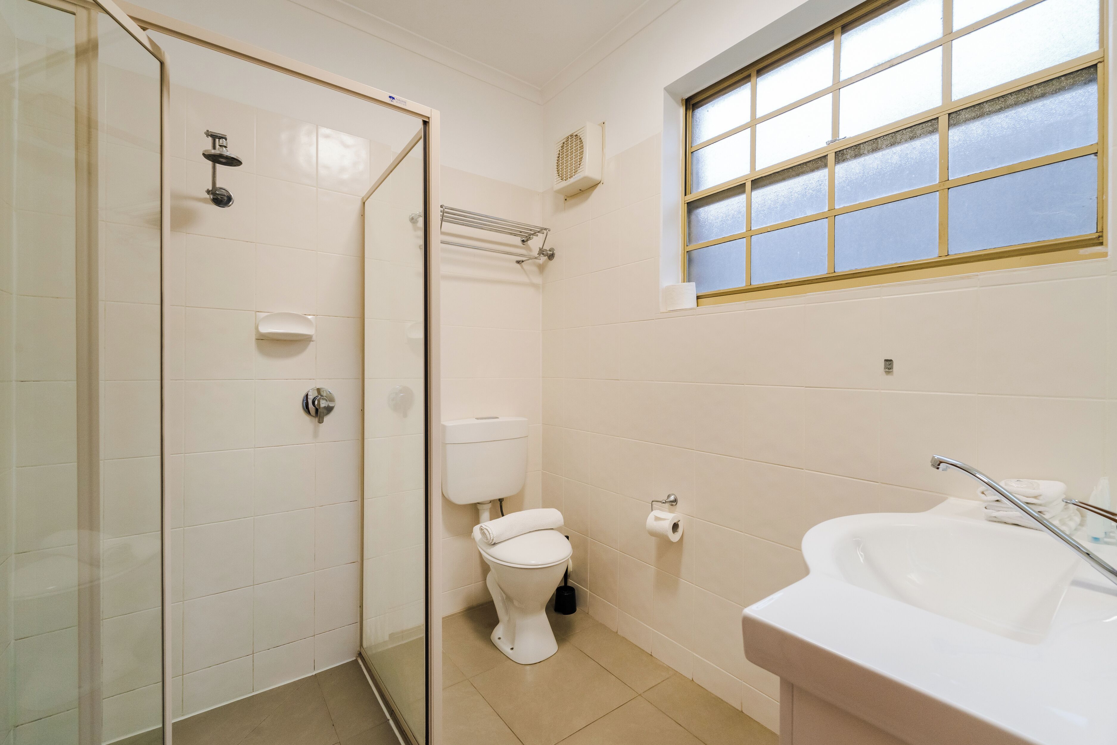 A bathroom with a shower, toilet, sink, and a window.