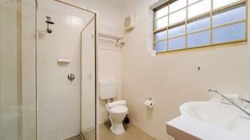 A bathroom with a shower, toilet, sink, and a window.