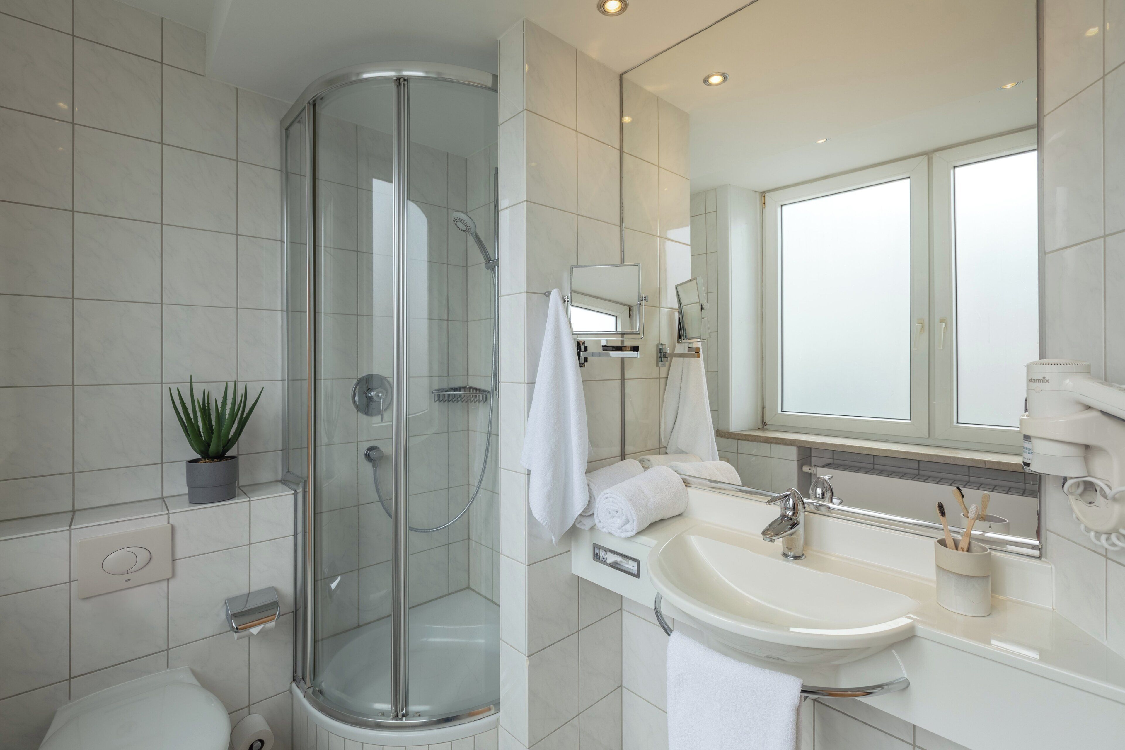 A modern bathroom with a glass shower enclosure, a sink, and a mirror.
