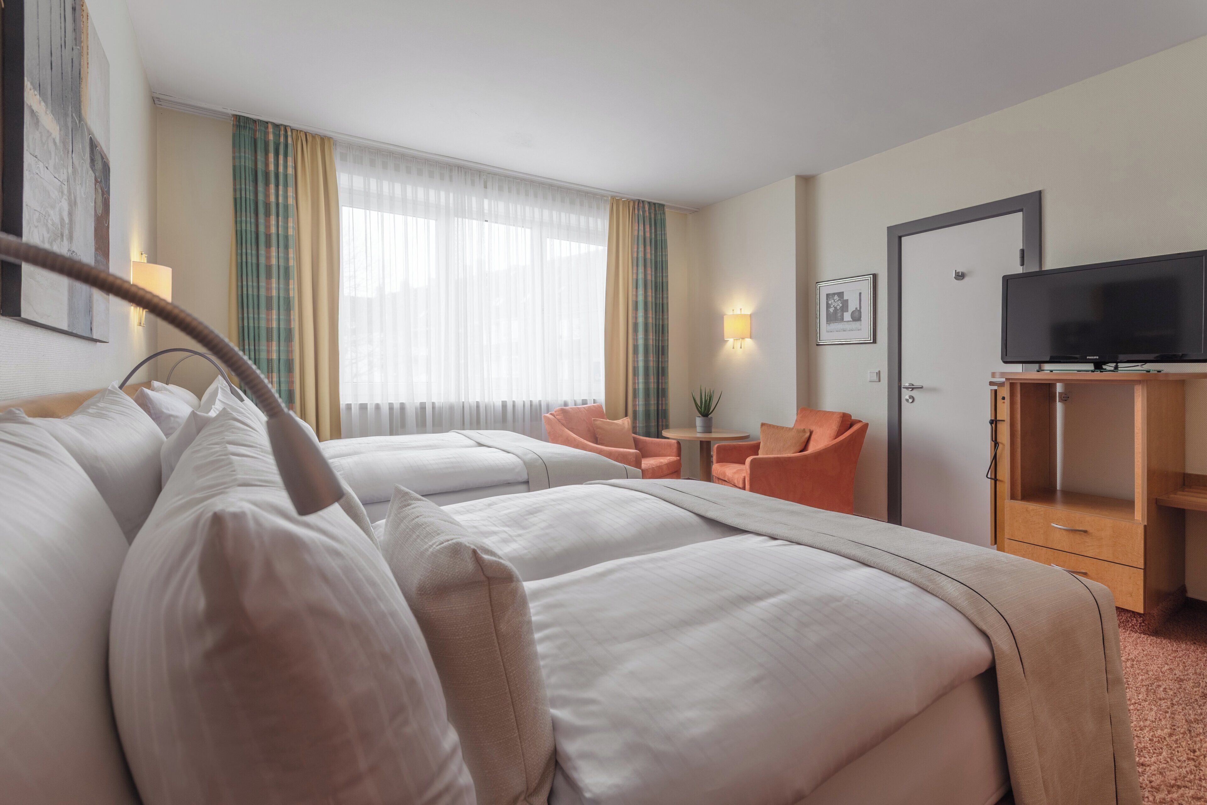 Une chambre d’hôtel avec deux lits, une télévision, un bureau et une chaise.